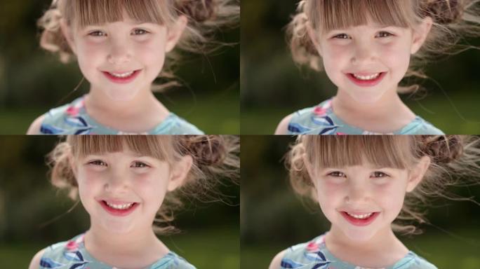 肖像快乐的小女孩带着顽皮的兴奋微笑着看着相机在阳光明媚的公园享受童年的乐趣4k镜头
