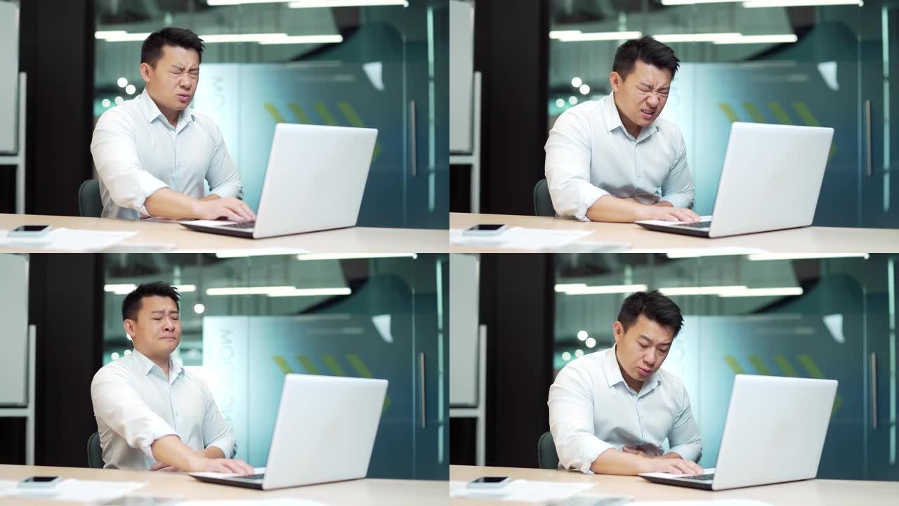 英俊的亚洲男性雇员企业家与严重的腹痛，胃痛，腹泻，坐在工作场所