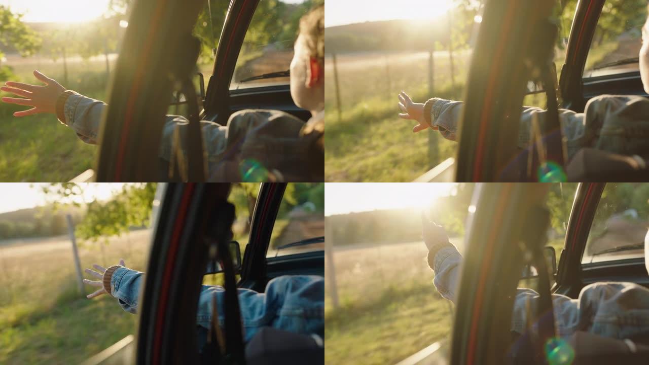 女人在车里牵着手走出窗户感觉风吹过手指在乡下开车暑假旅行享受日落路上的自由