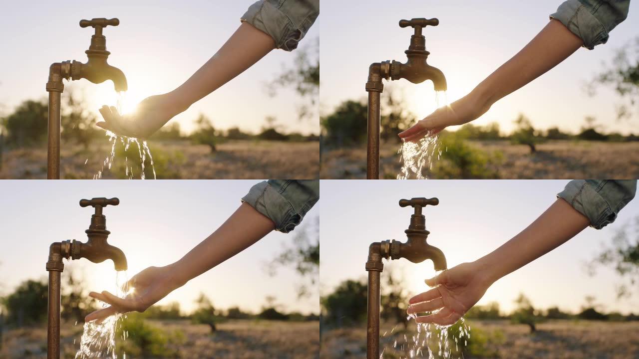 妇女在日出时在农村农田用淡水在水龙头下洗手