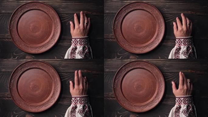 乌克兰妇女坐在国家餐厅等待点菜。女孩在等待盘子时紧张地敲手指在木桌上。空粘土板