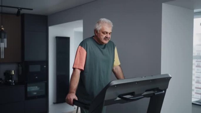 老年人健身，白发和胡须的老人在家中跑步机上行走