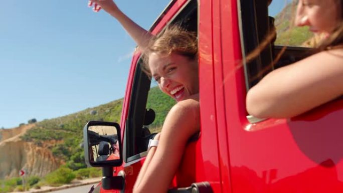 一群大笑的女性朋友在公路旅行中通过敞开车的侧窗挥舞