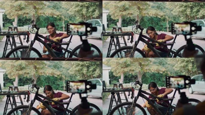 十几岁的女孩使用角磨机教学如何与朋友一起使用智能手机录制视频在家中的社交媒体在车库4k镜头对自行车进