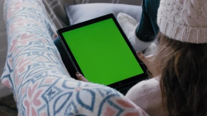 女人使用数字平板电脑观看绿屏放松在沙发上享受在线娱乐