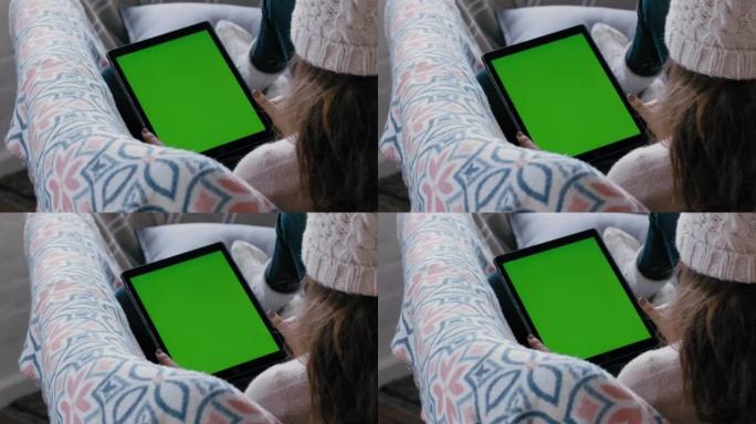 女人使用数字平板电脑观看绿屏放松在沙发上享受在线娱乐