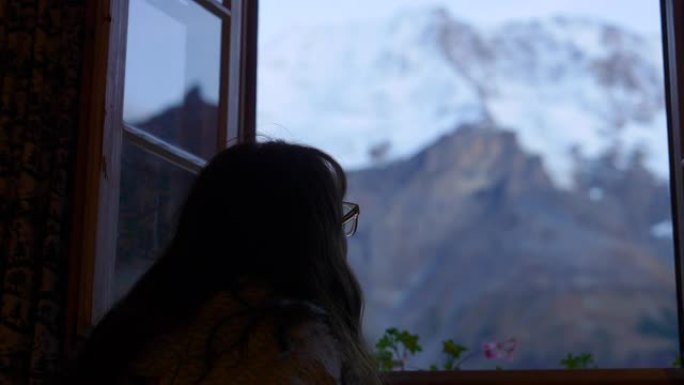 女人透过窗户看雪山