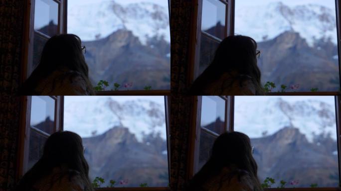 女人透过窗户看雪山