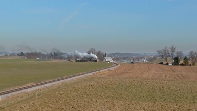 穿越乡村时，蒸汽旅客列车驶近，冒烟的鸟瞰图