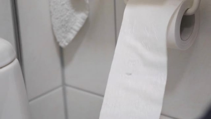 在厕所里，一个男人的手在支架上换了一卷卫生纸。