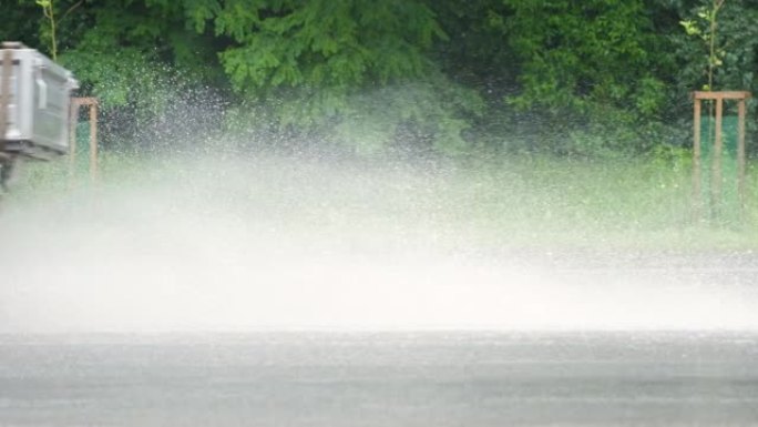 汽车快速行驶，在肮脏的雨水淹没的道路上留下喷雾飞溅。
