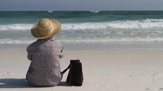 女人拿着包坐在沙滩上