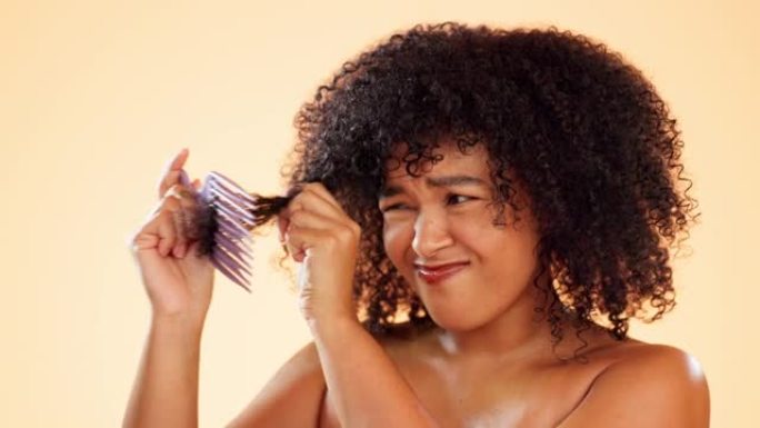 头发，梳子或缠结，在黄色背景下的工作室里的一名非洲裔妇女在护发中挣扎。美容，沙龙或发型以及发型师中不