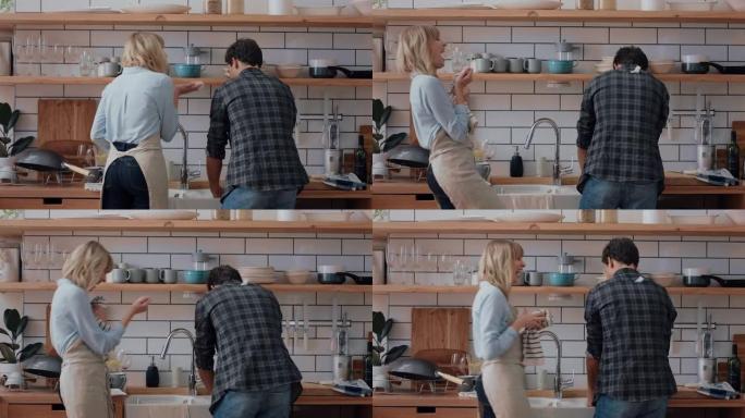 快乐的年轻夫妇洗碗在厨房玩得开心扔肥皂泡享受浪漫关系嬉戏做家务4k镜头