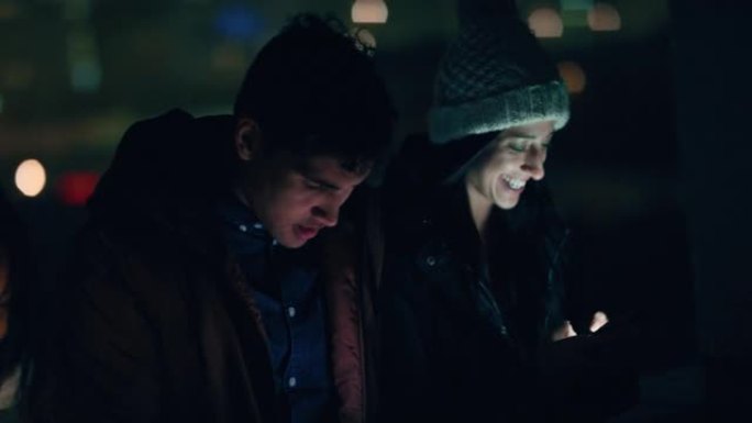 一群朋友晚上在屋顶上放松，使用智能手机技术浏览社交媒体在线聊天，享受周末聚会