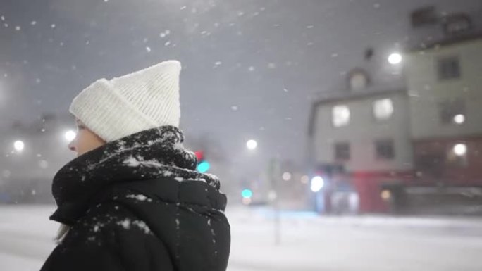 一个女人站在城市里，看着降雪