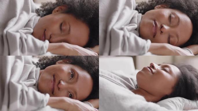 美丽的非洲裔美国妇女在睡个好觉后在床上醒来，微笑着为新的一天做好准备