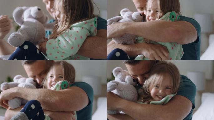 快乐的父亲在床上拥抱女儿小女孩笑着享受爸爸的拥抱