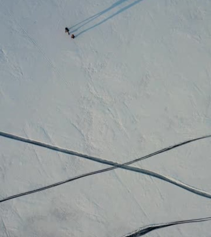 两名穿越雪场的旅行者的鸟瞰图