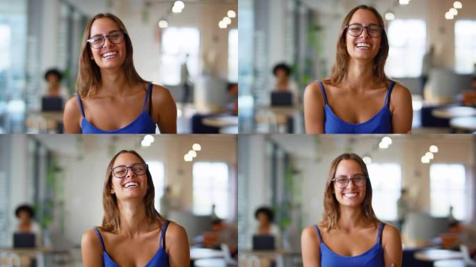 戴着眼镜站在繁忙的现代开放式办公室的年轻微笑女商人的肖像