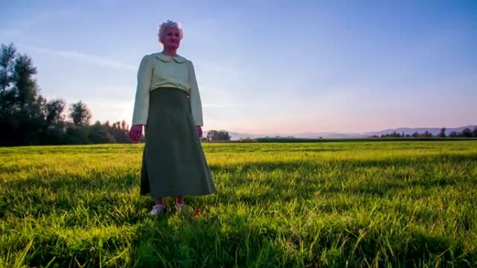 日落时站在田野上时，风吹老妇人的裙子