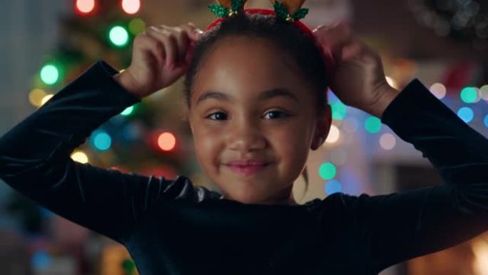 肖像可爱的非洲裔美国女孩庆祝圣诞节穿着有趣的驯鹿鹿角享受节日，五颜六色的灯光在家里玩得开心4k镜头