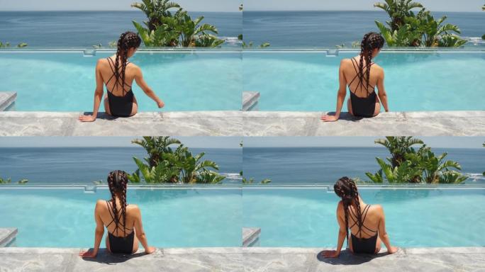 旅行女子坐在游泳池边嬉戏地抚摸着水面，在豪华酒店度假村享受美丽的海景，棕榈树穿着性感比基尼4k