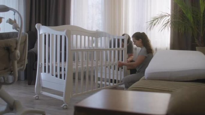 父母一起为新生婴儿组装白色婴儿床