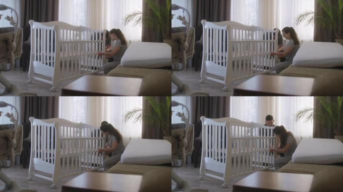 父母一起为新生婴儿组装白色婴儿床