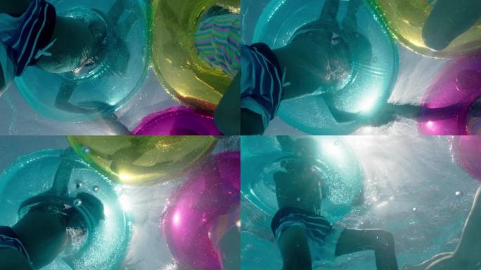儿童在游泳池里游泳，带彩色游泳管充气玩具嬉戏嬉戏地在水上一起玩乐漂浮着享受暑假水下景观