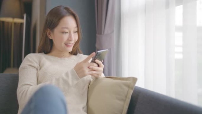 亚洲年轻女子在家使用手机。