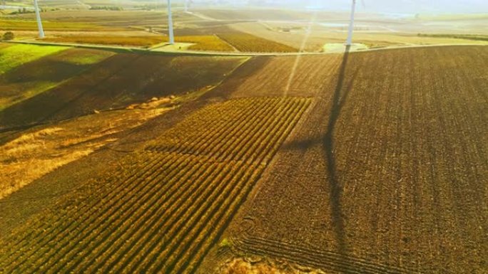 在晴朗的天空下，无人机拍摄的农业景观上的风力涡轮机。巨大的风力涡轮机在田野中间的线。