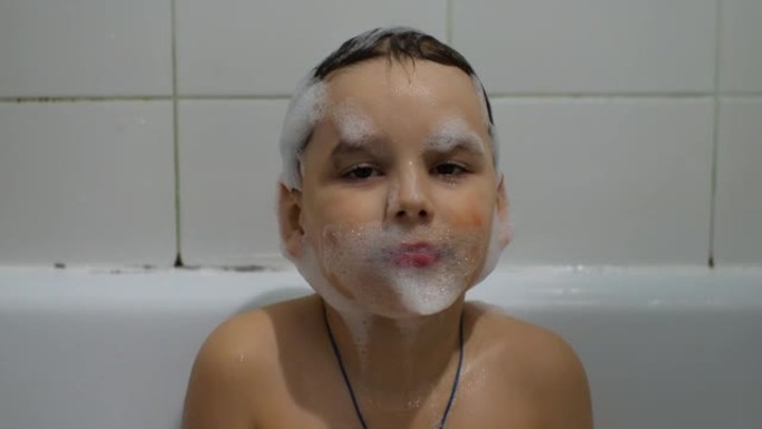 可爱的宝宝沉迷于沐浴泡沫。孩子的整个脸都被泡沫覆盖。这个男孩在浴缸里泡澡打扮。泡沫儿童的概念。