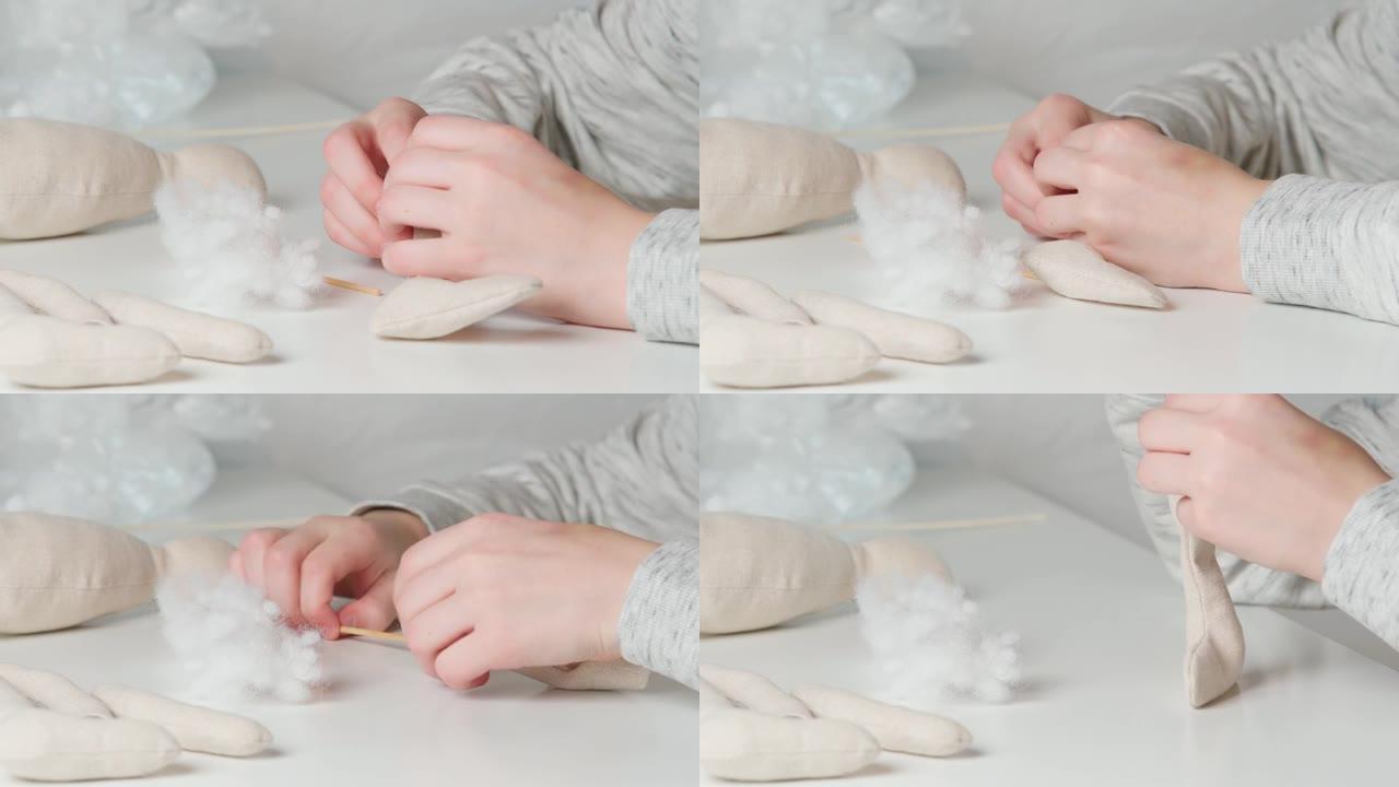视频制作毛绒玩具，制作爪子和身体，在桌子上装满棉花。特写裁缝裁缝手