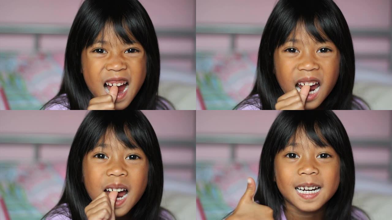 亚洲女孩扭动她的第一颗松动的牙齿