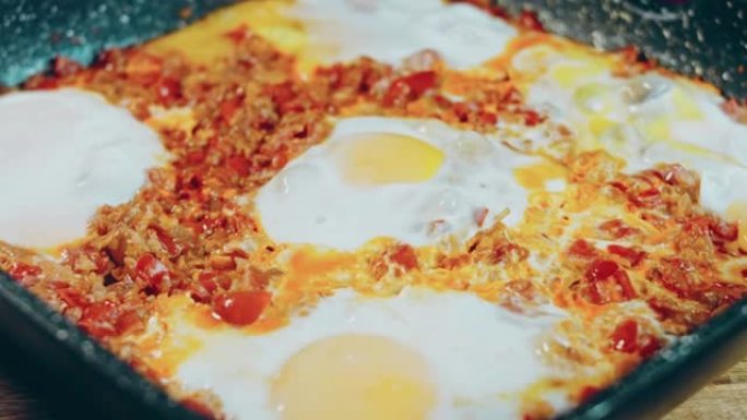 女人把装有chirbuli的锅放在桌子上。格鲁吉亚菜煎蛋，chirbuli。鸡蛋西红柿在锅里蒸，蜡烛