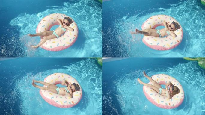 自上而下: 微笑的小女孩在漂浮的甜甜圈上，用双腿泼水