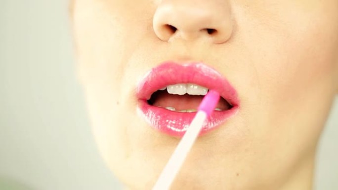 女人在嘴唇上涂抹粉红色唇彩，特写