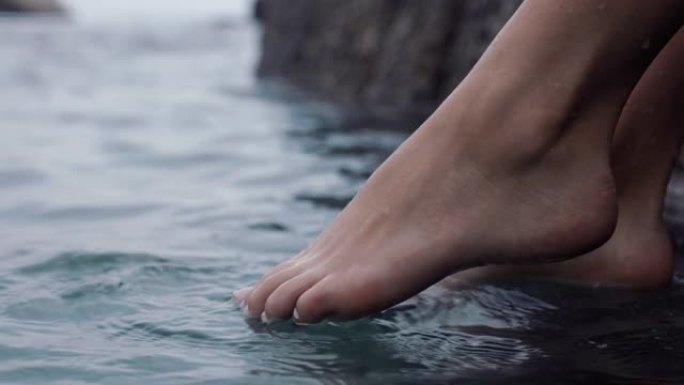 特写女人的脚在水中嬉戏赤脚享受平静的海滩海边