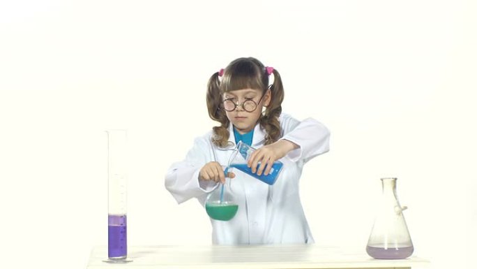 严肃的，穿着制服和圆形眼镜的马尾辫小女孩做化学实验 -- 混合，站在桌子旁，孤立在白色背景上