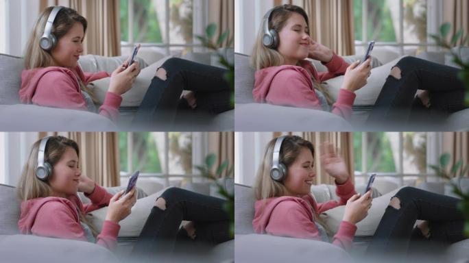 快乐的少女戴着耳机听音乐，在家沙发上放松，用智能手机发短信，享受在社交媒体上分享生活方式