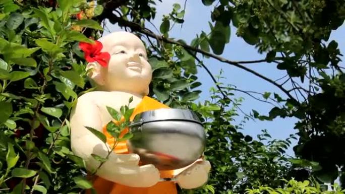 胖乎乎的佛教雕像拿着捐赠碗