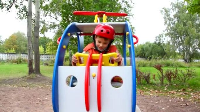 男孩在玩具直升机上秋千，儿童游乐场