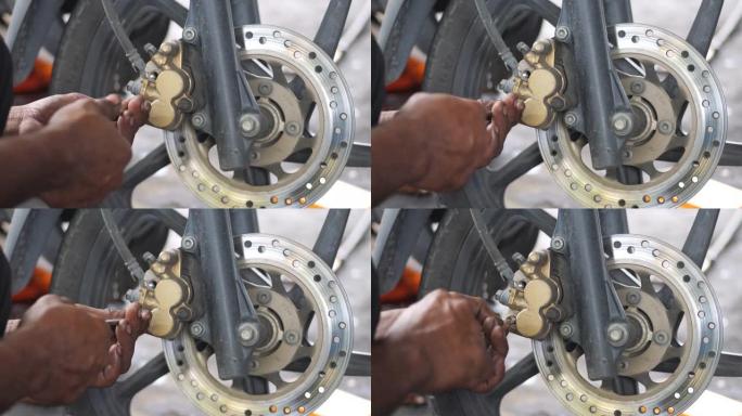 机械师更换和调整摩托车后制动系统，维护，修理车库中的摩托车概念。选择性聚焦