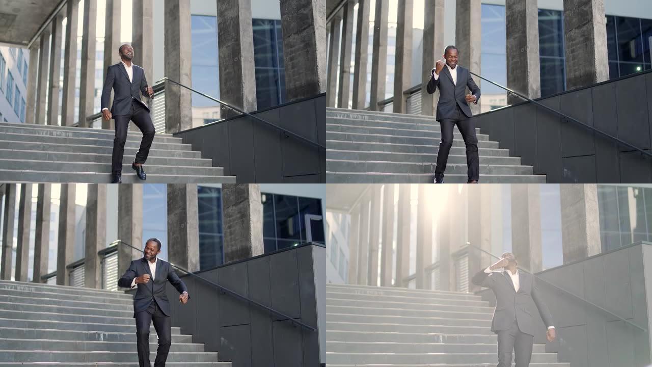 快乐兴奋的非洲裔美国商人庆祝成功快乐地跑下办公楼的楼梯穿着正装的中年男子正在跳舞，双手以胜利的姿态举