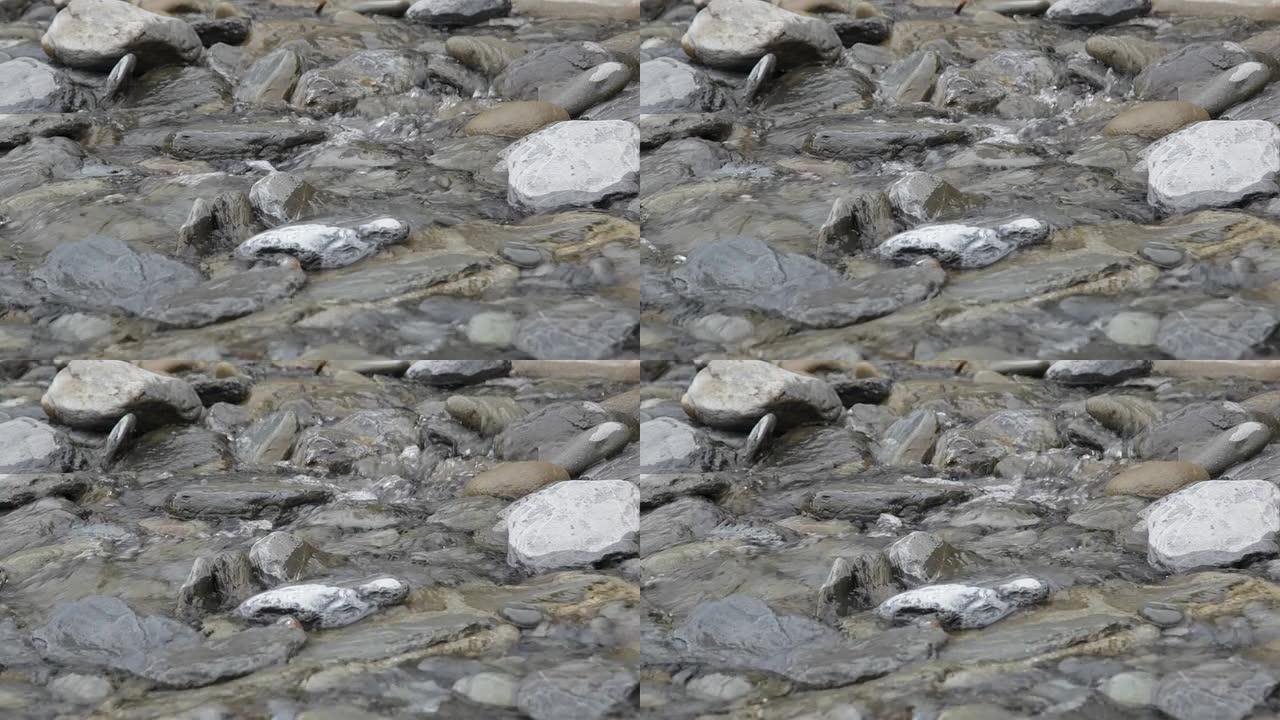 纯山溪流中的透明水在石头上流动