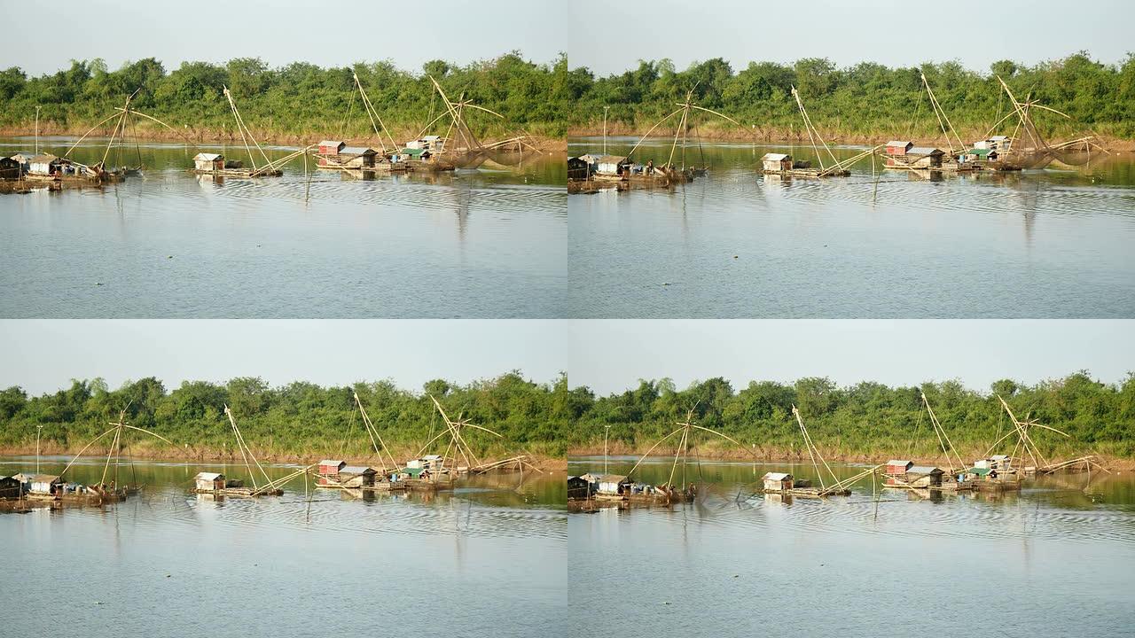 河上的船屋和中国渔网; 渔民将中国渔网从水中抬起