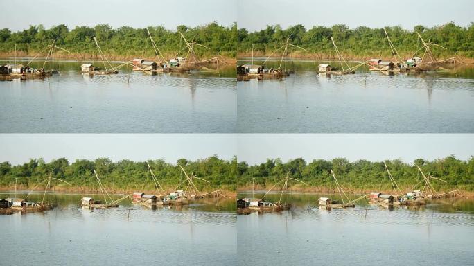 河上的船屋和中国渔网; 渔民将中国渔网从水中抬起