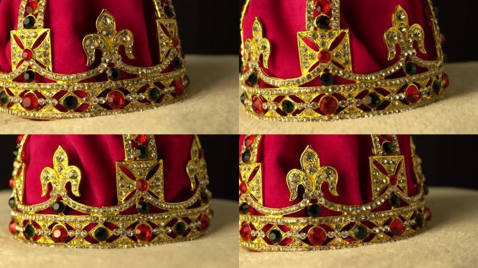 仪式加冕钻石皇冠底部的极端宏观特写由金色和红色皇家软天鹅绒材料制成。黑色背景。慢速旋转运动。4k，u