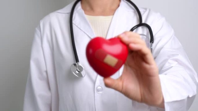 医生手握红色心形在医院。爱心，捐赠者，世界心脏日，世界卫生日，企业社会责任捐赠和保险概念